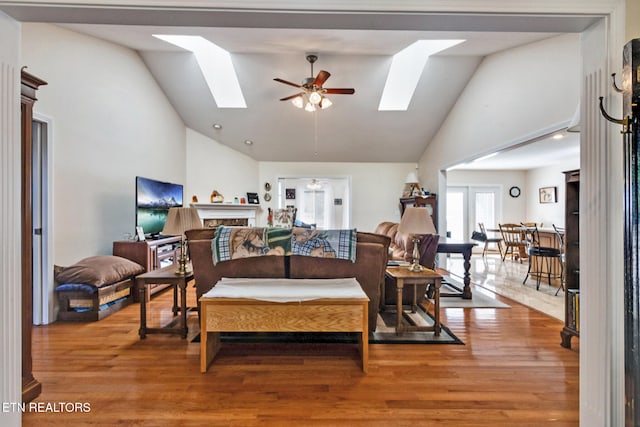 living room with a skylight, ceiling fan, and wood finished floors