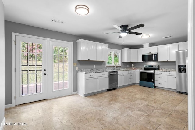 kitchen featuring stainless steel appliances, sink, white cabinets, and light stone counters