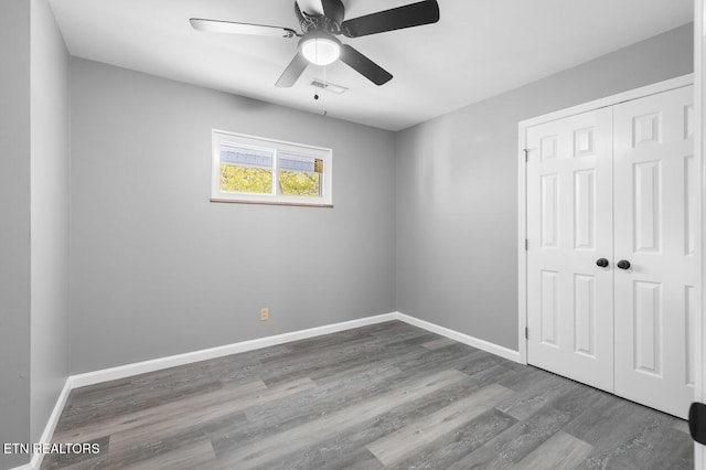 unfurnished bedroom featuring ceiling fan, hardwood / wood-style floors, and a closet