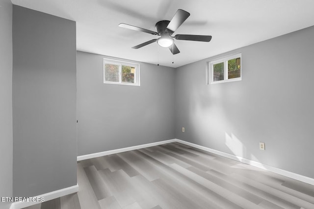 empty room featuring ceiling fan, a wealth of natural light, and wood-type flooring