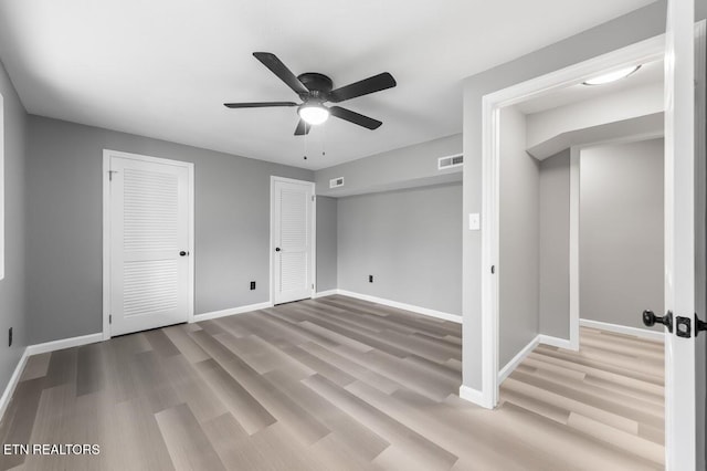 unfurnished bedroom with multiple closets, ceiling fan, and light wood-type flooring