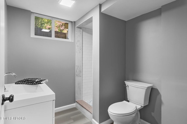 bathroom with a shower, hardwood / wood-style floors, vanity, and toilet