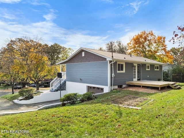 back of property with a wooden deck, a garage, and a yard