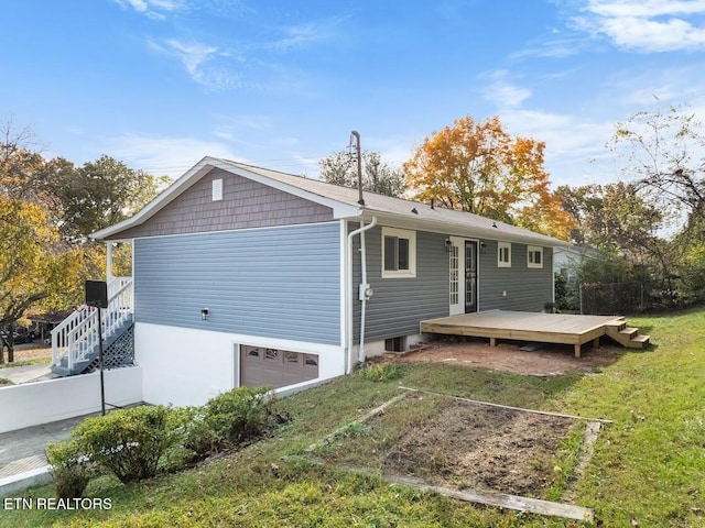 exterior space featuring a garage, a wooden deck, and a lawn