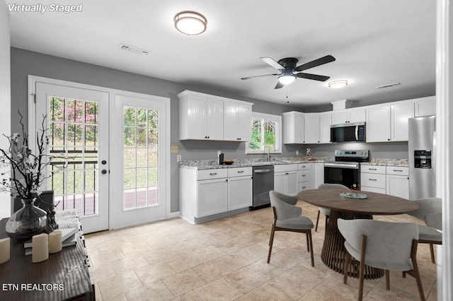 kitchen featuring appliances with stainless steel finishes, sink, white cabinets, light stone countertops, and french doors