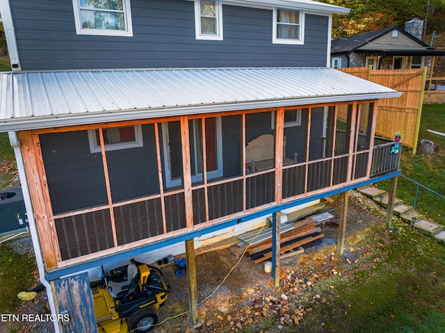 rear view of property with central AC and a sunroom