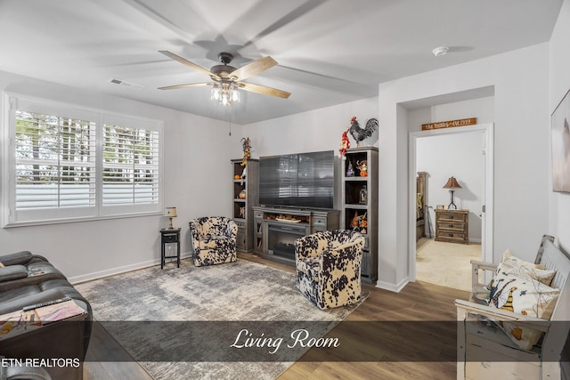 living room featuring dark wood-type flooring and ceiling fan