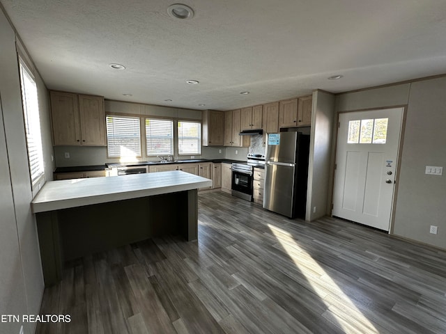 kitchen with a kitchen breakfast bar, a healthy amount of sunlight, stainless steel appliances, and dark wood-type flooring