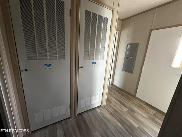 hallway featuring hardwood / wood-style floors, electric panel, and crown molding