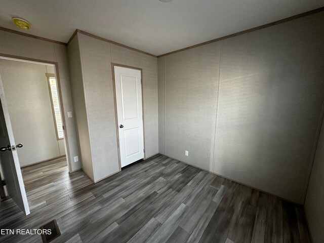 unfurnished bedroom featuring crown molding and wood-type flooring