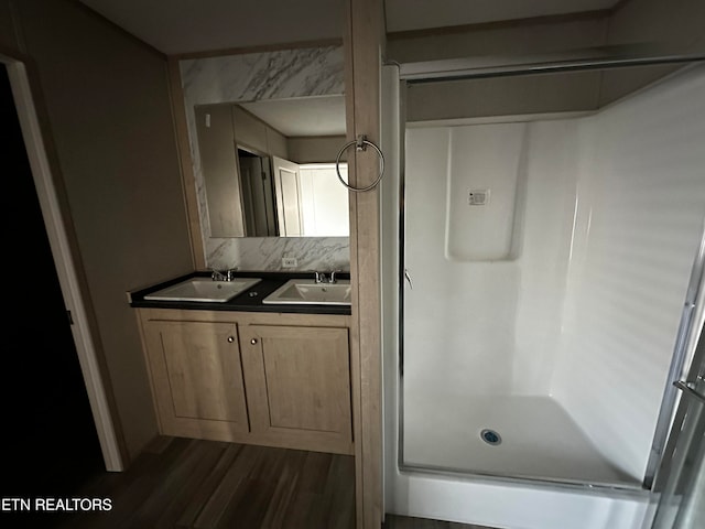 bathroom with vanity, backsplash, walk in shower, and wood-type flooring