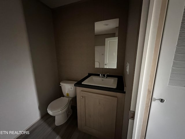 bathroom with vanity, toilet, and hardwood / wood-style flooring