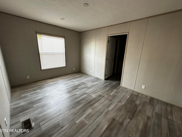 unfurnished room with a textured ceiling and hardwood / wood-style flooring