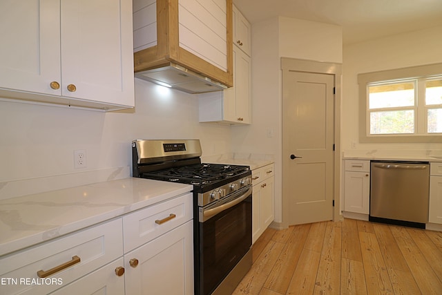 kitchen with light wood-type flooring, white cabinetry, light stone countertops, and stainless steel appliances
