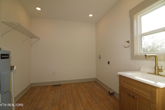 laundry room featuring electric dryer hookup, hookup for a washing machine, sink, gas water heater, and light hardwood / wood-style floors