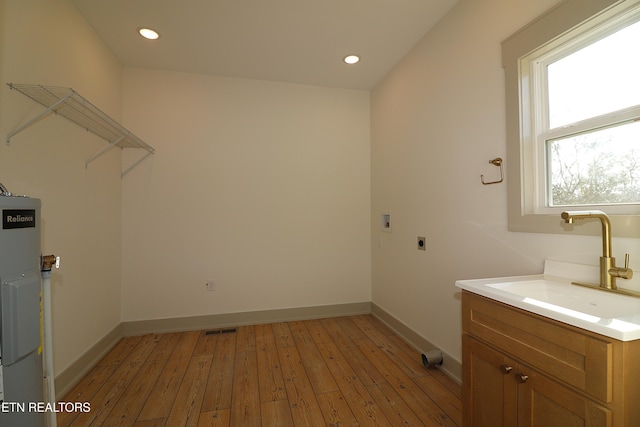 washroom featuring hookup for an electric dryer, laundry area, a sink, baseboards, and light wood-style flooring
