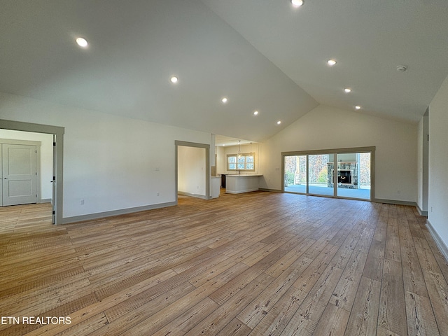 unfurnished living room featuring recessed lighting, high vaulted ceiling, baseboards, and light wood finished floors