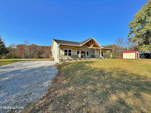 view of front of house featuring a front yard, board and batten siding, a porch, a storage shed, and an outbuilding