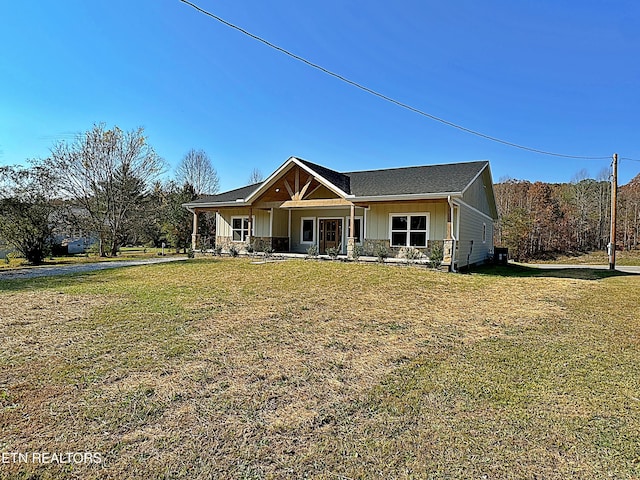 rear view of house featuring covered porch, board and batten siding, a yard, and stone siding