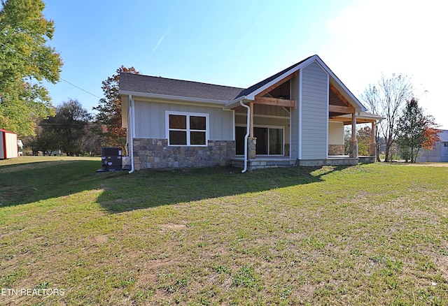 exterior space with central air condition unit, board and batten siding, stone siding, and a front yard
