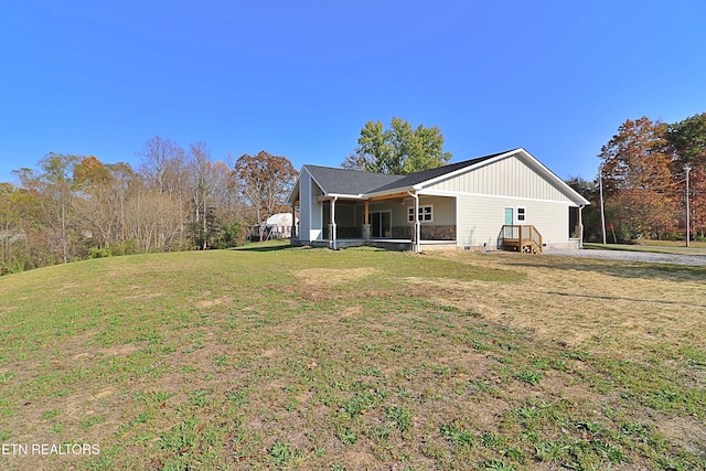 back of property with a yard, driveway, and a sunroom