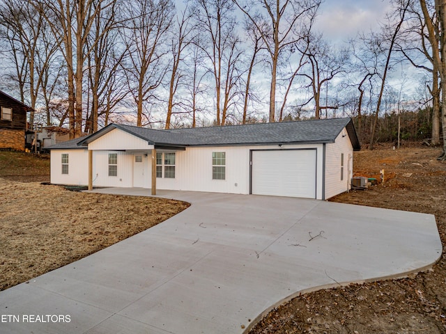 single story home featuring central air condition unit, covered porch, and a garage