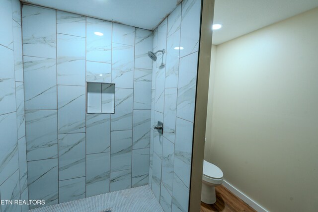 bathroom with hardwood / wood-style floors, toilet, and tiled shower