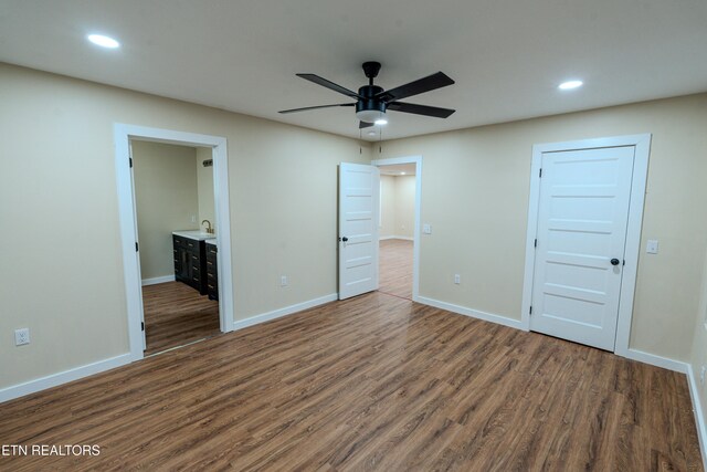 unfurnished bedroom featuring ceiling fan, sink, dark wood-type flooring, and connected bathroom