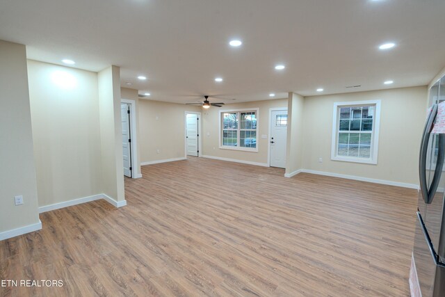 basement featuring stainless steel fridge, light hardwood / wood-style flooring, and ceiling fan