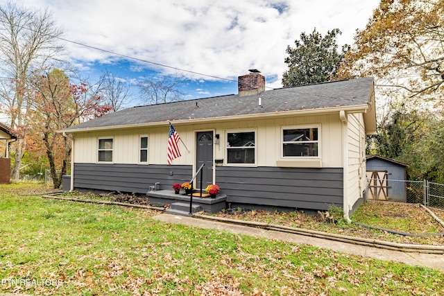 view of front of home featuring a storage unit and a front yard