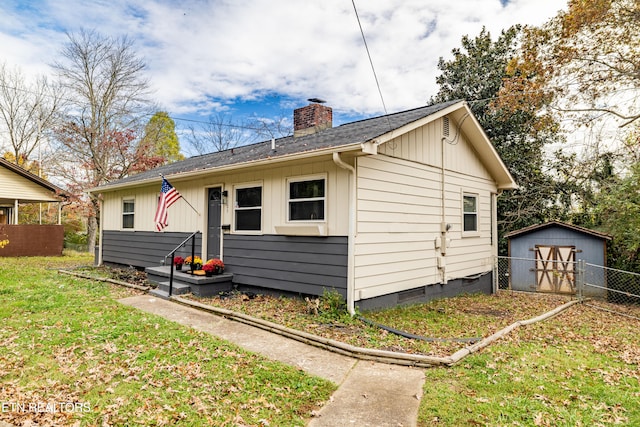 rear view of property with a storage unit and a yard