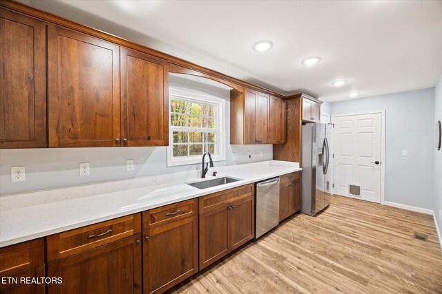 kitchen with appliances with stainless steel finishes, light hardwood / wood-style flooring, and sink