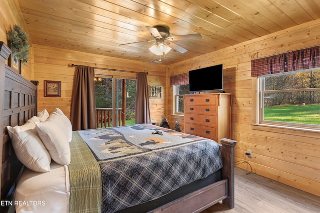 bedroom with multiple windows, wooden walls, and hardwood / wood-style flooring