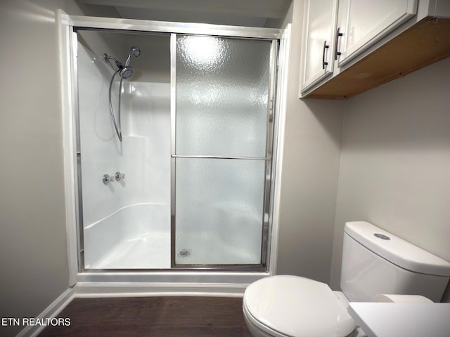 bathroom featuring walk in shower, wood-type flooring, and toilet