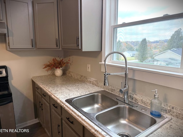 kitchen featuring gray cabinetry, sink, stainless steel range with electric stovetop, and exhaust hood