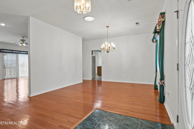 empty room featuring dark wood-type flooring and ceiling fan with notable chandelier