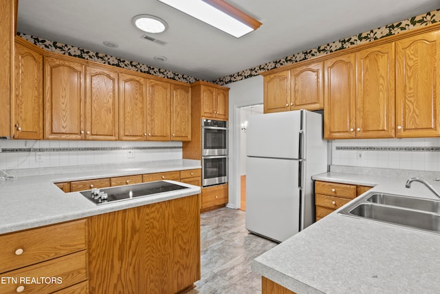 kitchen with black electric stovetop, white refrigerator, sink, tasteful backsplash, and double oven