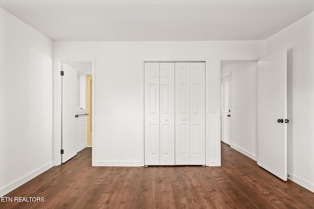 unfurnished bedroom with dark wood-type flooring and a closet
