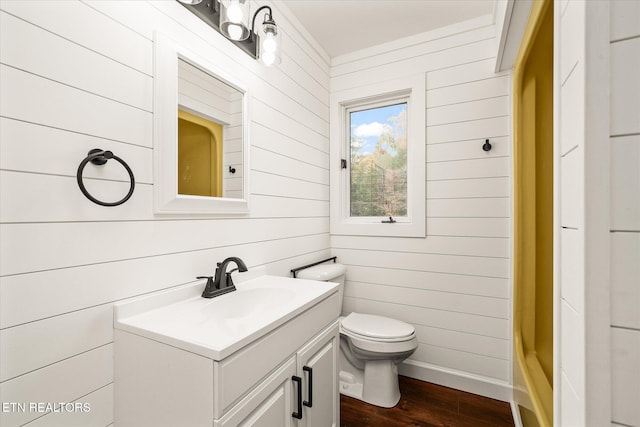 bathroom featuring wood walls, wood-type flooring, toilet, walk in shower, and vanity