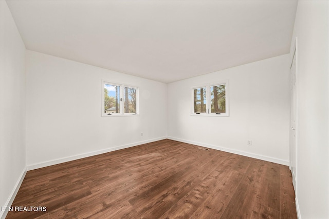 spare room featuring a wealth of natural light and dark wood-type flooring