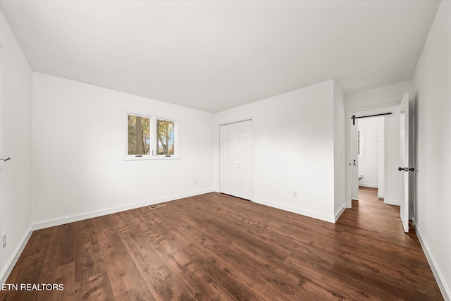 unfurnished room featuring a barn door and dark hardwood / wood-style flooring