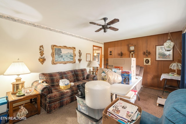 carpeted living room featuring ceiling fan and wood walls