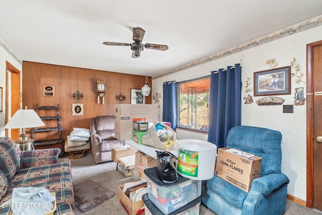 carpeted living room with ceiling fan and wood walls