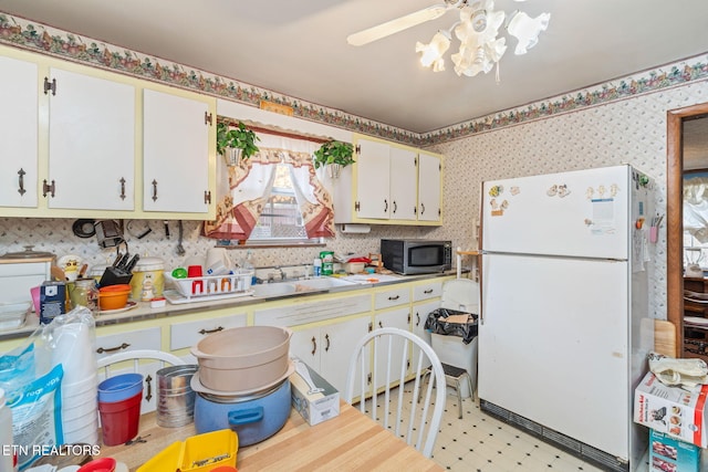 kitchen with white fridge, sink, and white cabinets