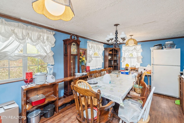 dining space featuring ornamental molding, a chandelier, wood-type flooring, and a textured ceiling