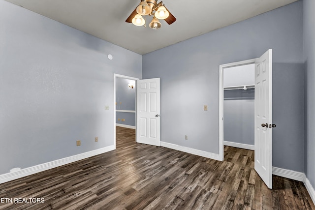 unfurnished bedroom with dark hardwood / wood-style flooring, a closet, a walk in closet, and ceiling fan