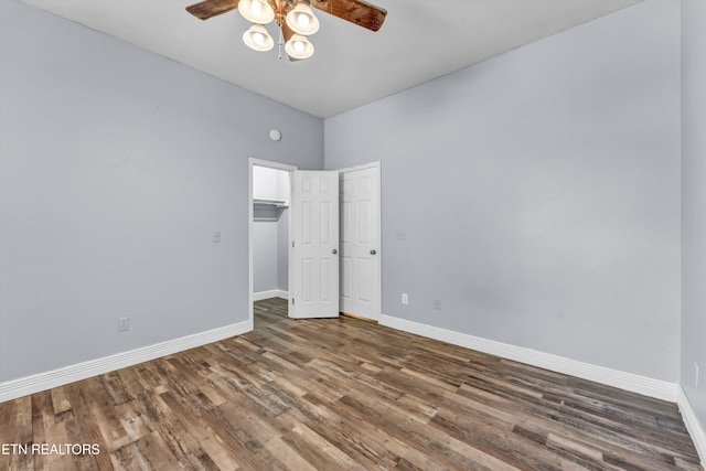 unfurnished bedroom featuring a towering ceiling, a spacious closet, a closet, ceiling fan, and dark wood-type flooring