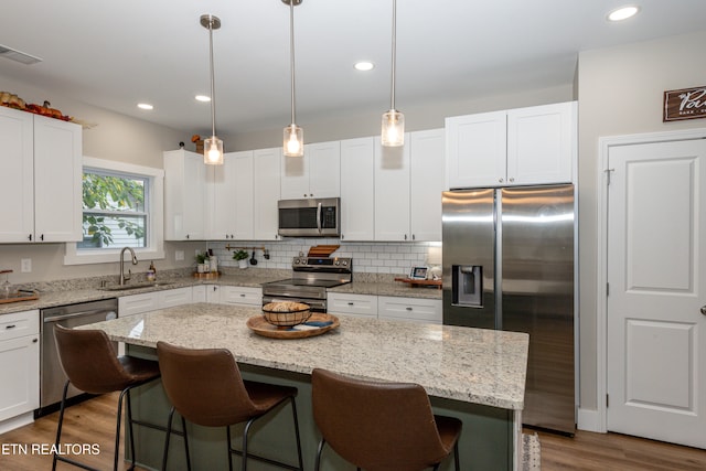 kitchen with a kitchen island, wood-type flooring, sink, white cabinetry, and appliances with stainless steel finishes