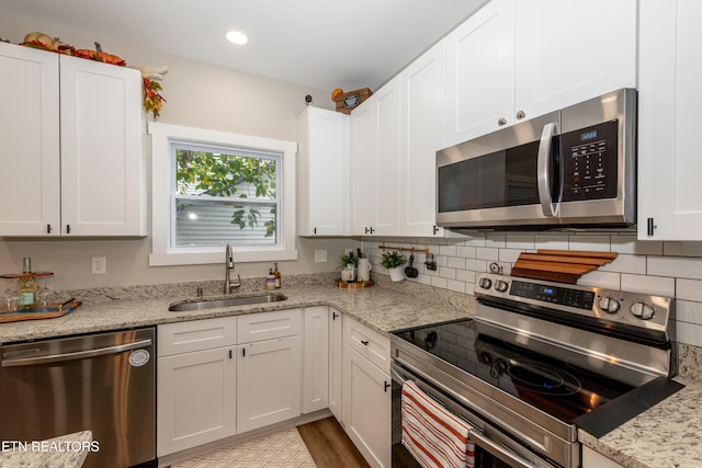 kitchen featuring light stone countertops, sink, white cabinetry, and stainless steel appliances