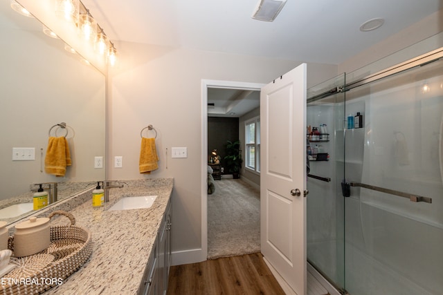 bathroom with a shower with door, hardwood / wood-style flooring, and vanity